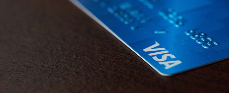 a blue visa card on a dark colored surface